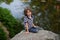 Cute little boy sitting on the shore of a small lake