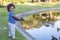 Cute little boy smiling as he learns to fish in a pond at an outdoor park.