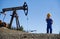 Cute little boy standing near pump jack in oil field.