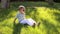 A cute little boy in sunglasses sitting on the green grass in the park.