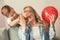 Cute little boy surprising his mother with balloon at home