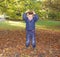 Cute little boy throwing colorful leaves