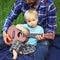 Cute little boy with ukulele is sitting on the lap of his father. Father teaches his son to play on the ukulele Hawaiian guitar