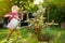 Cute little boy watering plants blue spruce in the garden at summer sunny day