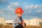 Cute little boy wearing helmet sitting on the new buildings background at sunset