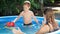 Cute little boy with young mother playing in swimming pool with toy ship or boat. Concept of happy and cheerful family