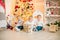 Cute little boys  with blond hair plays with little girl  in a bright room decorated with Christmas garlands