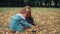 Cute little brother and sister playing in the autumn park, boy throws on girl yellow fallen leaves 4k