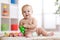 Cute little caucasian boy 8 months old sits and plays with toys in nursery room