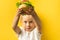 Cute little caucasian girl with blonde hair enjoying burger on a yellow background.