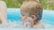 Cute little child bathing in blue street pool in courtyard. Portrait of joyful toddler, baby. Kid laughs, splashes water