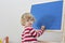 Cute little child drawing with chalk on a blackboard at home, creative and funny indoor activity for children