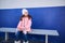 Cute little child girl looking aside, sitting on the banc, waiting for train on the railway station platform