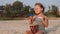 Cute little child girl playing drums on sandy beach.