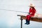 Cute little child girl in rubber boots and straw hat fishing from wooden pier near glass jar and little fish on a lake. Family