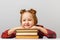 Cute little child girl sitting at the table, leaning on thick books. Education concept