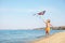 Cute little child with kite running at beach on day