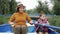 Cute little child resting in park with granny. Adorable boy rows boat on lake in park. Little boy sits in boat and holds oars. Hap