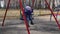 A cute little child sits on a swing in the playground in the spring