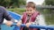 Cute little child talking and smiling at camera on lake. Adorable child sailing on wooden boat at park. Little happy boy clings to