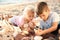Cute little children looking at sea shells through magnifying glass on beach