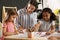 Cute little children with nursery teacher drawing at table in kindergarten