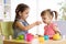 Cute little children playing with kitchenware while sitting at table at home or kindergarten