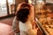 Cute little curly girl 3 years old with a young red-haired mother in the bakery at the counter chooses pastries. Cafe