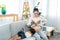 cute little daughter lying on mom\'s lap playing mobile phone and a pregnant Asian single mom reading a book comfortably