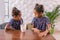 Cute little daughters looking at each other angrily after arguing in cafeteria