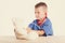 Cute little doctor boy with smile on face sitting at his desk on white background. Intelligent children in doctor suit with blue