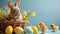 Cute little easter bunny in the basket with colorful eggs and yellow little chickens. Free space for text over blue