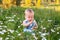 Cute little funny baby child sitting in chamomile field