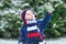 Cute little funny child in colorful winter fashion clothes having fun and playing with snow, outdoors during snowfall