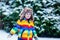 Cute little funny kid boy in colorful winter fashion clothes having fun and playing with snow, outdoors during snowfall