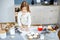 Cute little girl in the apron cooks cookies in kitchen.