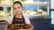 Cute little girl in an apron working at the bakery holding a basket with pastry