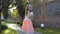 Cute little girl with basket of flowers in hand posing for camera in the garden