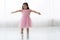 Cute little girl in beautiful dress is dancing at light sunny room.
