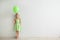 Cute little girl in Birthday hat and with balloon near light wall