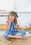 Cute little girl in blue dress eats a cake and licks her fingers