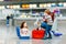 Cute little girl and boy at airport. Tired children, siblings sitting on ground and waiting for delayed flight. Kids