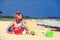 Cute little girl building sandcastle on beach