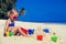 Cute little girl building sandcastle on tropical beach