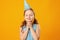 Cute little girl celebrates birthday. The child closed his eyes and made a wish. Closeup portrait on yellow background