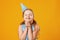 Cute little girl celebrates birthday. The child closed his eyes and made a wish. Closeup portrait on yellow background