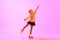 Cute little girl, child in sweater and skirt training figure skating, dancing against pink background in neon light