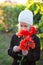 Cute little girl in a coat and hat holding a bouquet of poppy flowers in the spring
