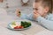 Cute little girl covering mouth and refusing to eat dinner in kitchen