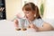 Cute little girl with cup of hot cocoa drink and cookies at home